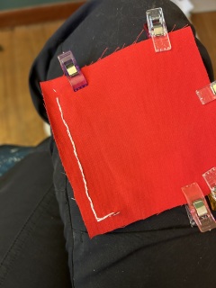 My hand sewing isn't terrible a hand-sewn seam in white thread on red fabric